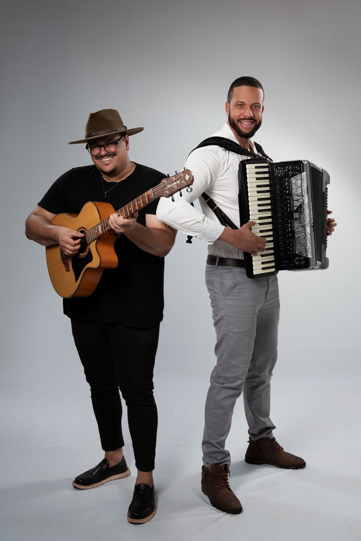 A dupla em pé com instrumentos